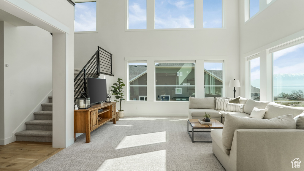 Living area featuring plenty of natural light, a towering ceiling, and stairway