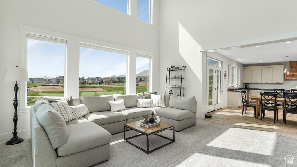 Living room featuring recessed lighting, light wood finished floors, plenty of natural light, and a towering ceiling
