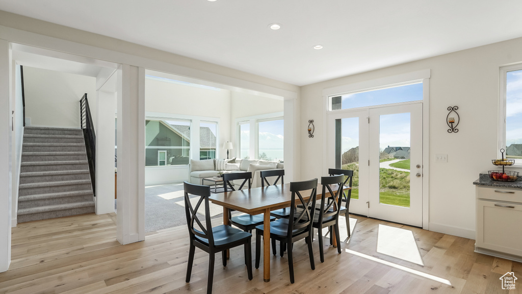Dining area with light wood-style flooring, recessed lighting, and stairway