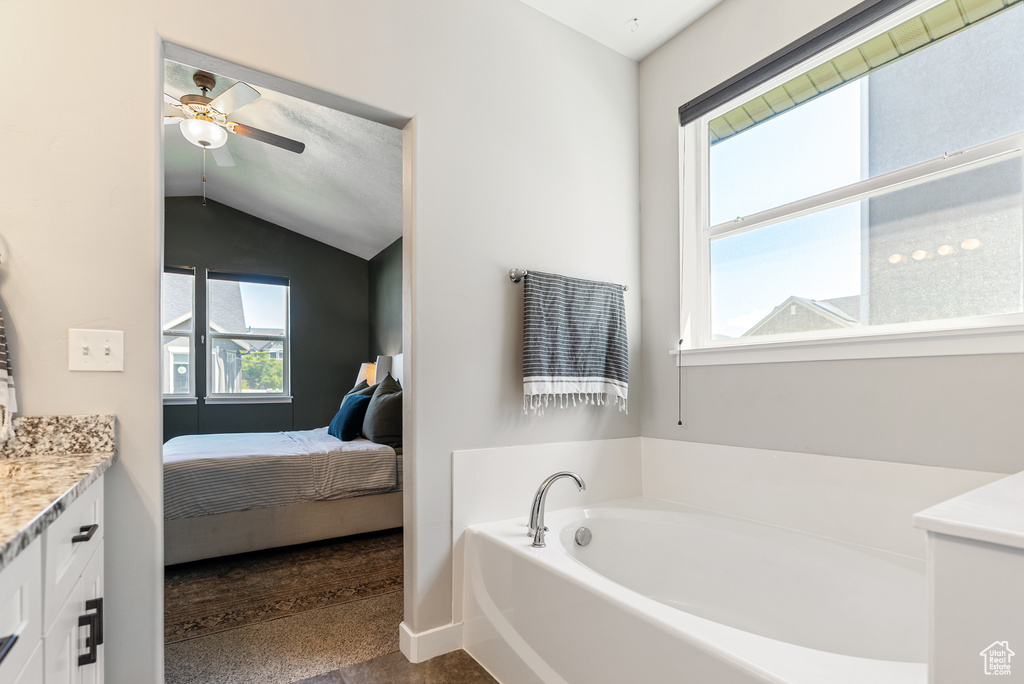 Full bath with a garden tub, ensuite bath, vanity, lofted ceiling, and a ceiling fan