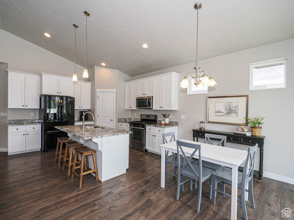 Kitchen featuring stainless steel appliances, a sink, a center island with sink, vaulted ceiling, and a notable chandelier