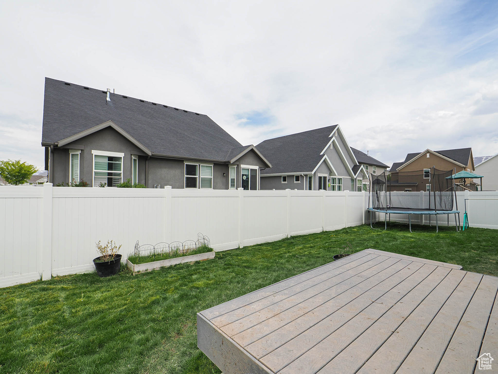 View of yard with a residential view, a trampoline, a fenced backyard, and a deck