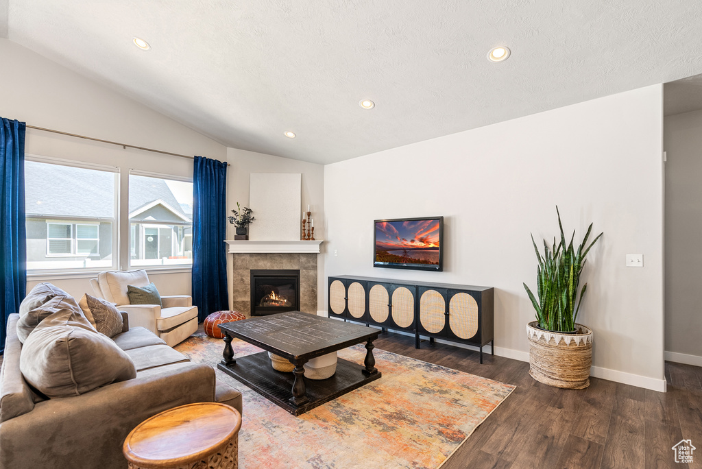 Living area with lofted ceiling, wood finished floors, recessed lighting, baseboards, and a fireplace