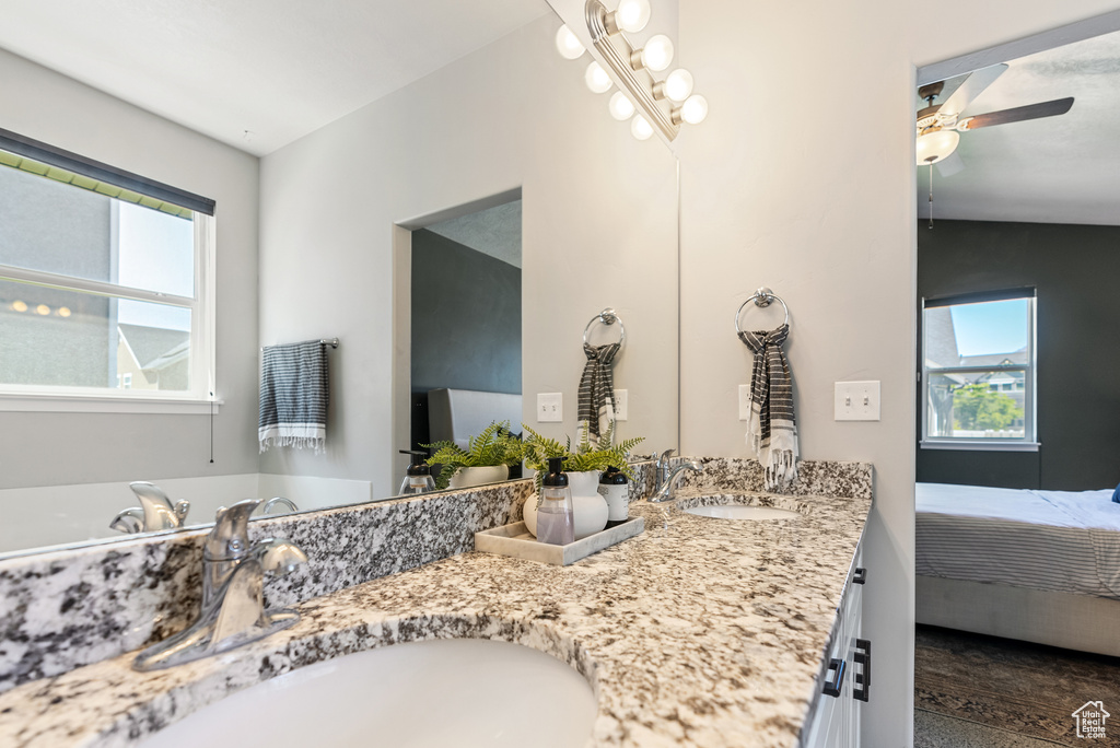 Full bath featuring ceiling fan, double vanity, and connected bathroom