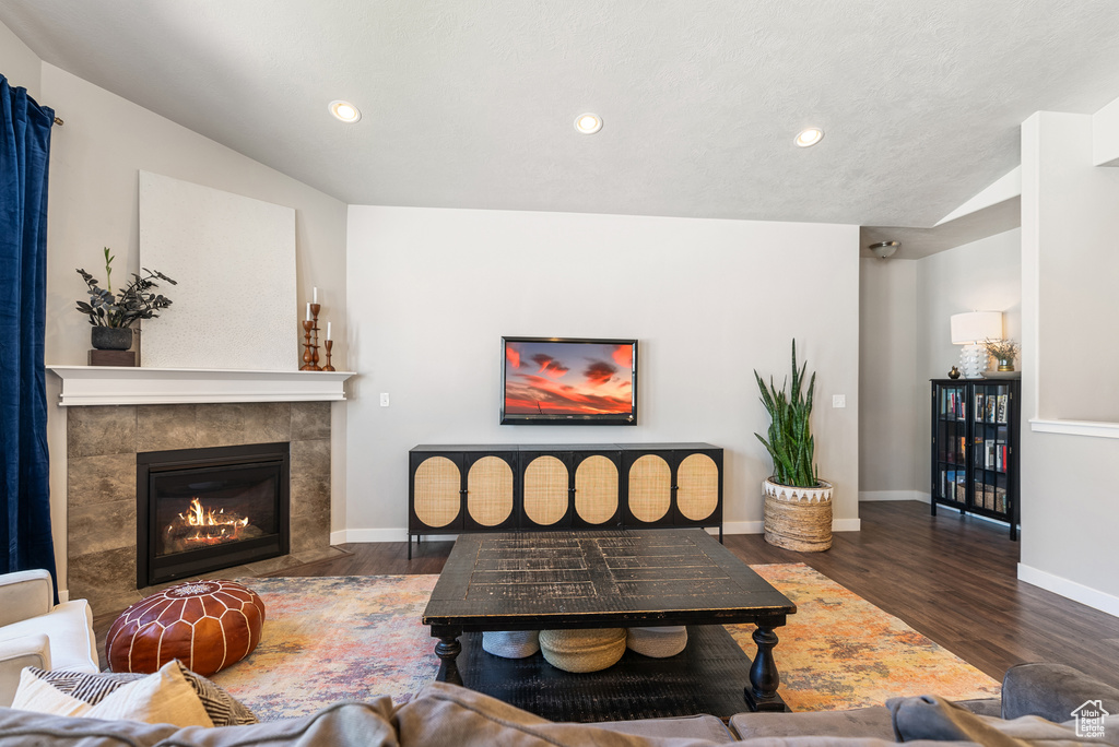 Living room with wood finished floors, baseboards, recessed lighting, and a tiled fireplace