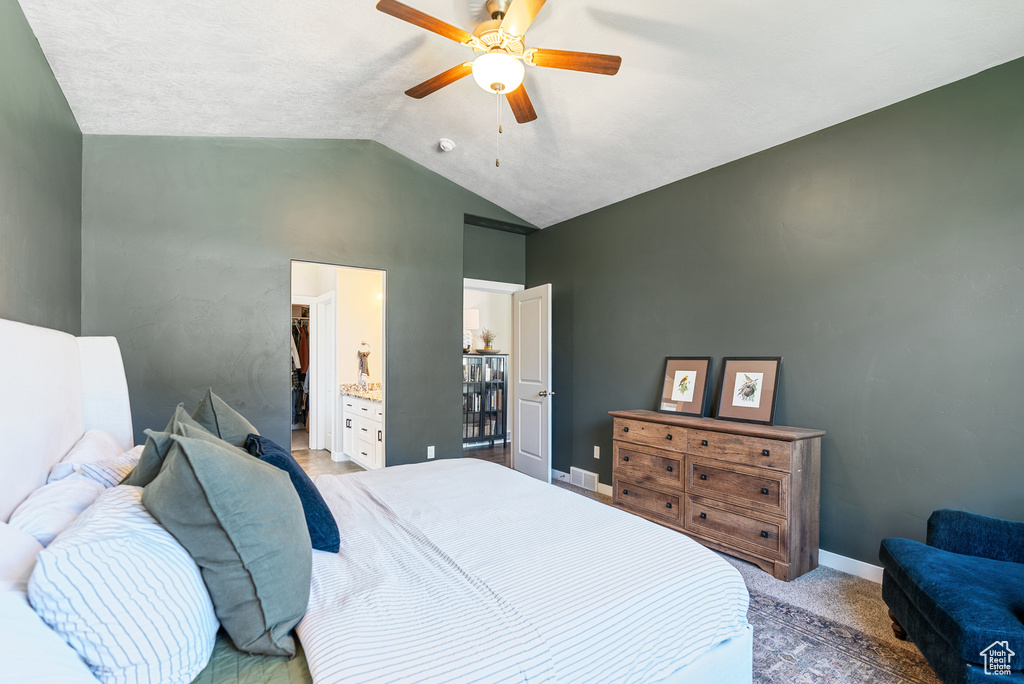 Bedroom with vaulted ceiling, light carpet, baseboards, a ceiling fan, and connected bathroom