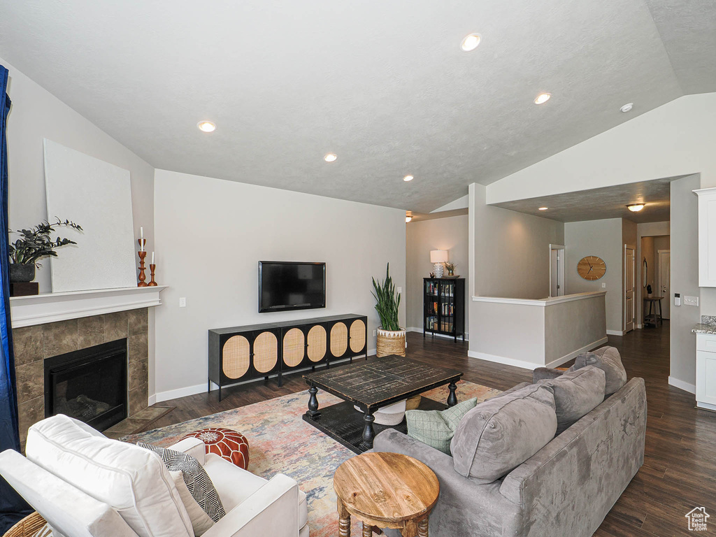 Living room with recessed lighting, a tile fireplace, dark wood-style floors, vaulted ceiling, and baseboards