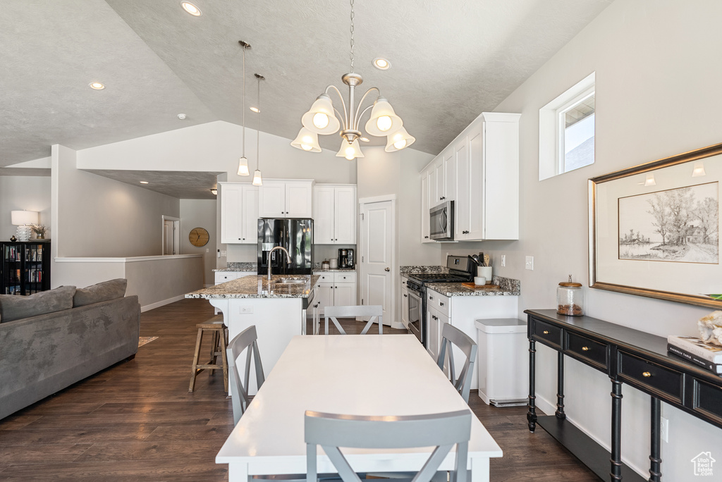 Dining space featuring a chandelier, dark wood-type flooring, and high vaulted ceiling