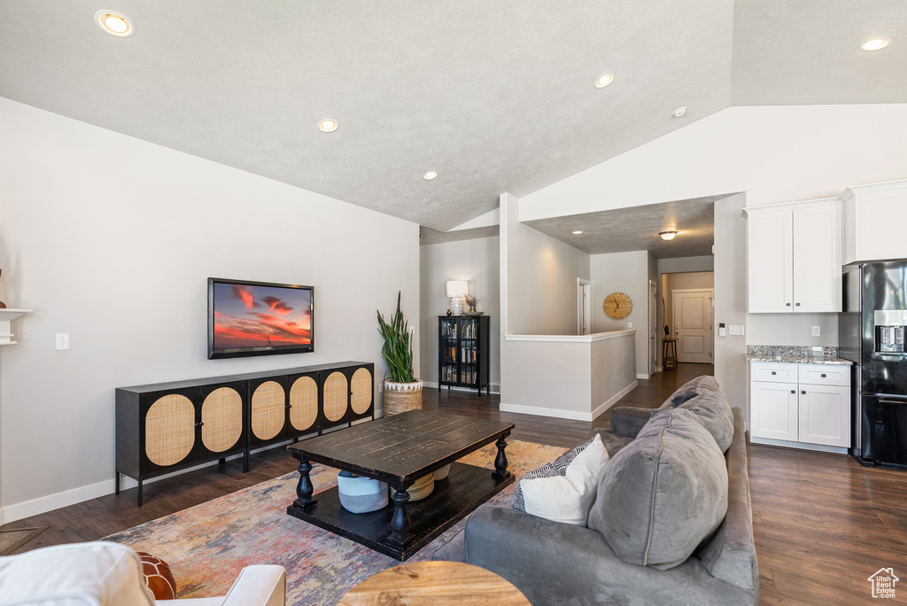 Living area featuring vaulted ceiling, dark wood finished floors, recessed lighting, and baseboards