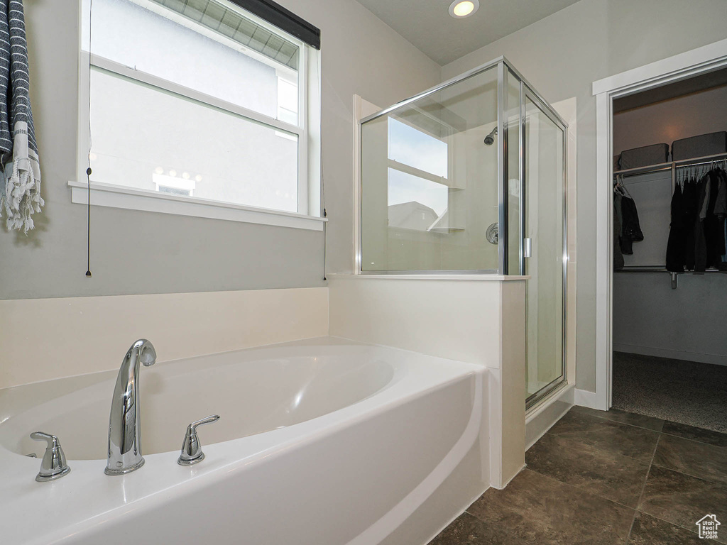 Full bath featuring a walk in closet, stone finish floor, a garden tub, and a stall shower