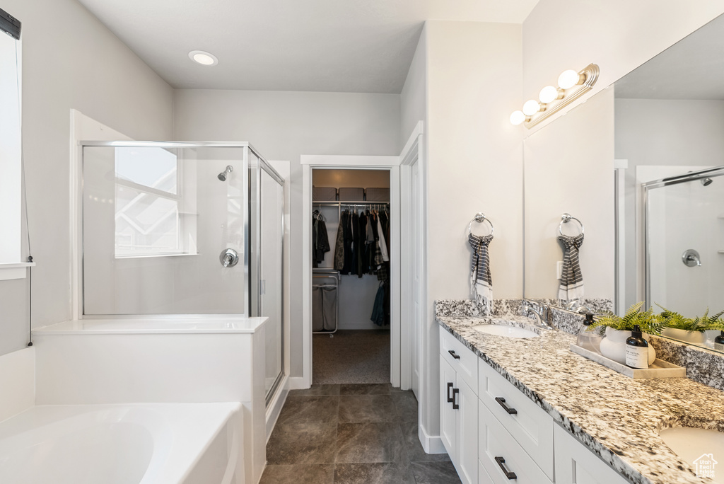 Full bath with a shower stall, double vanity, a bath, and a spacious closet