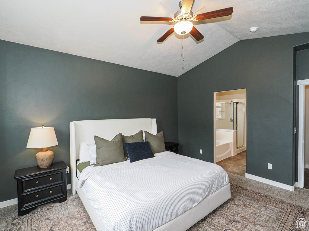 Carpeted bedroom with vaulted ceiling, baseboards, ensuite bathroom, and a ceiling fan