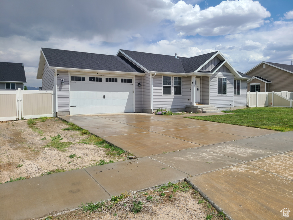 Ranch-style house featuring a garage, fence, driveway, and a gate