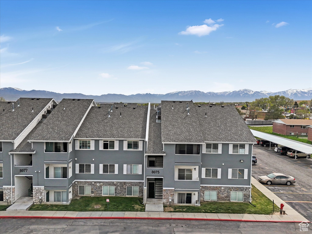 Exterior space with stone siding, a shingled roof, a mountain view, and stucco siding