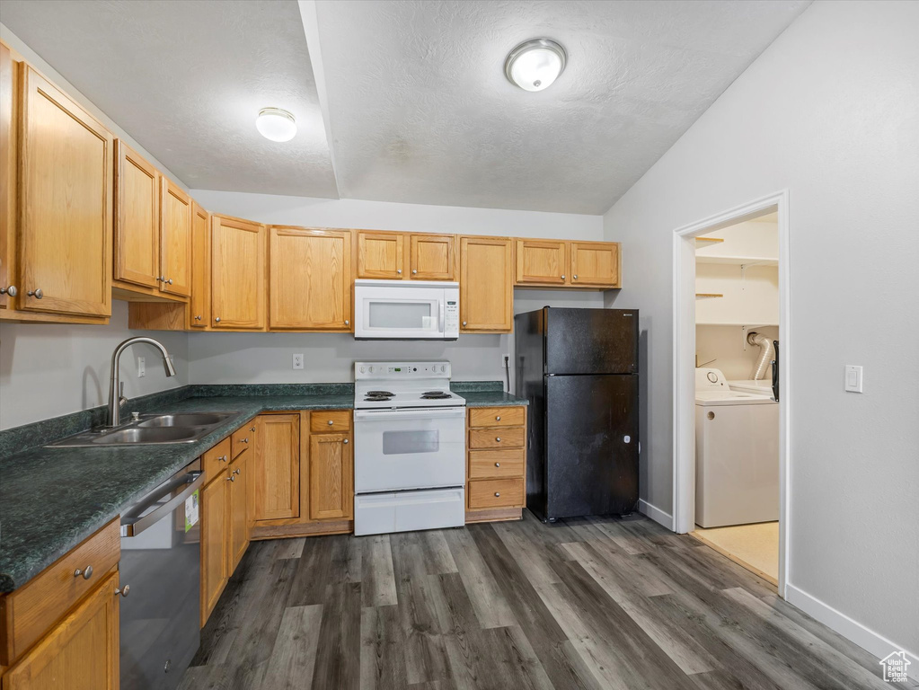 Kitchen featuring a sink, dark countertops, lofted ceiling, white appliances, and independent washer and dryer