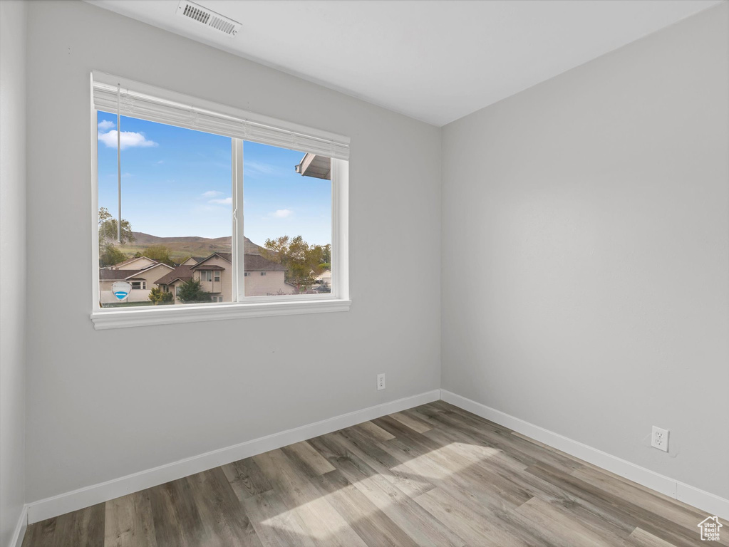 Empty room with baseboards, wood finished floors, and visible vents