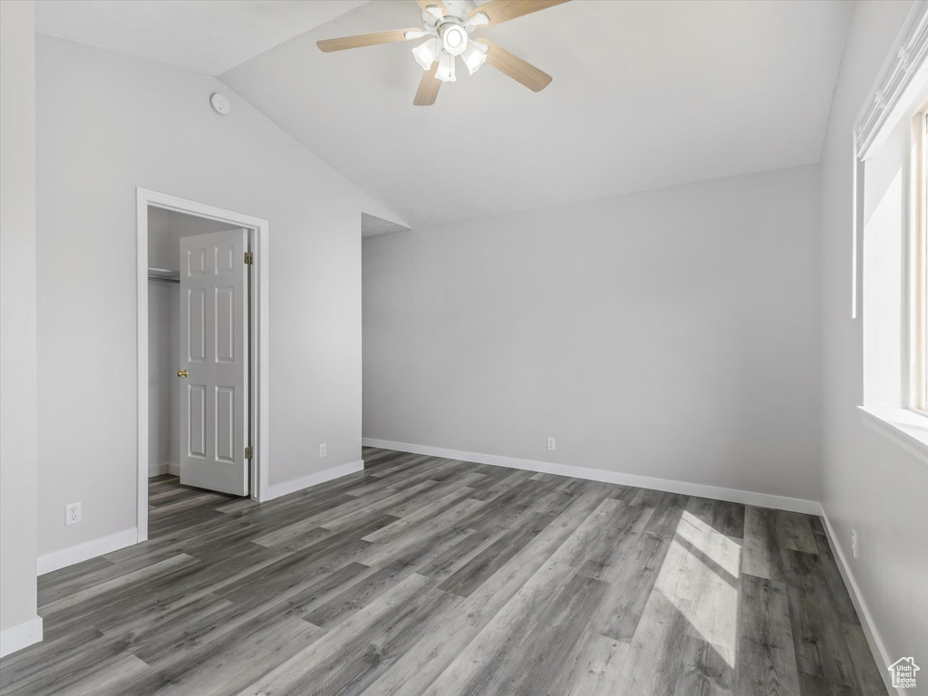 Unfurnished bedroom featuring vaulted ceiling, a ceiling fan, wood finished floors, and baseboards