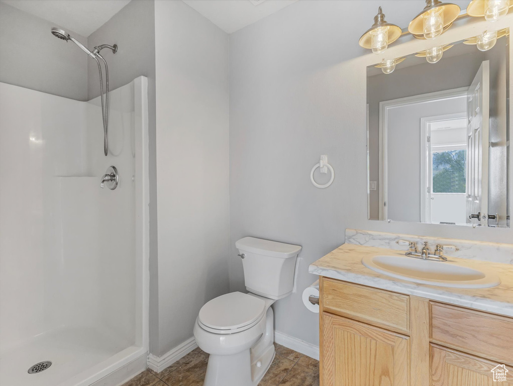 Full bathroom featuring baseboards, vanity, a shower stall, and toilet