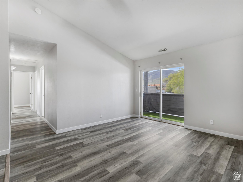 Empty room with wood finished floors, visible vents, and baseboards