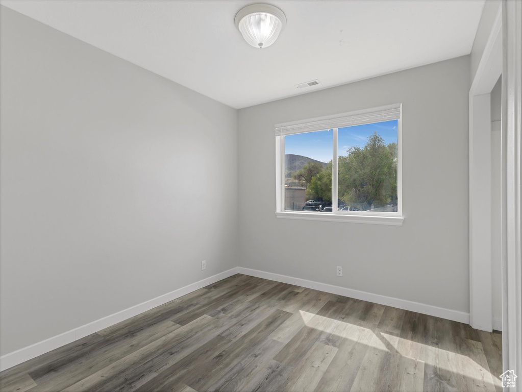 Unfurnished room featuring baseboards, wood finished floors, and visible vents