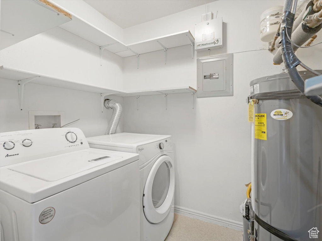 Washroom featuring washer and clothes dryer, electric panel, secured water heater, baseboards, and laundry area
