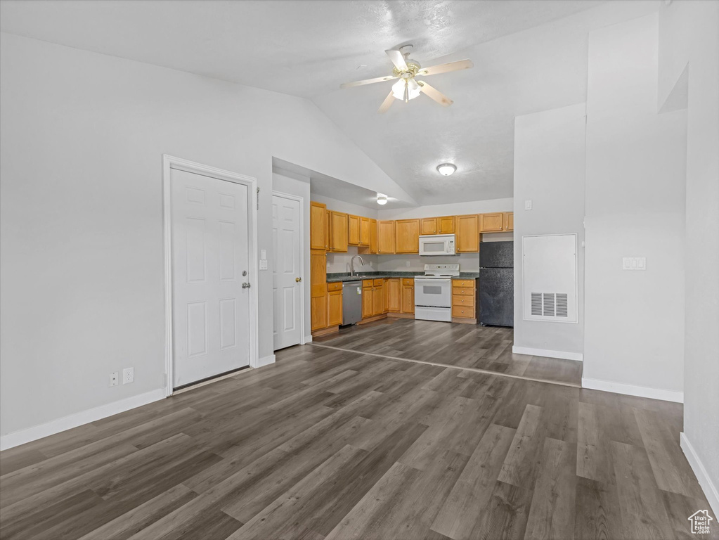 Unfurnished living room featuring dark wood-style floors, vaulted ceiling, a ceiling fan, a sink, and baseboards
