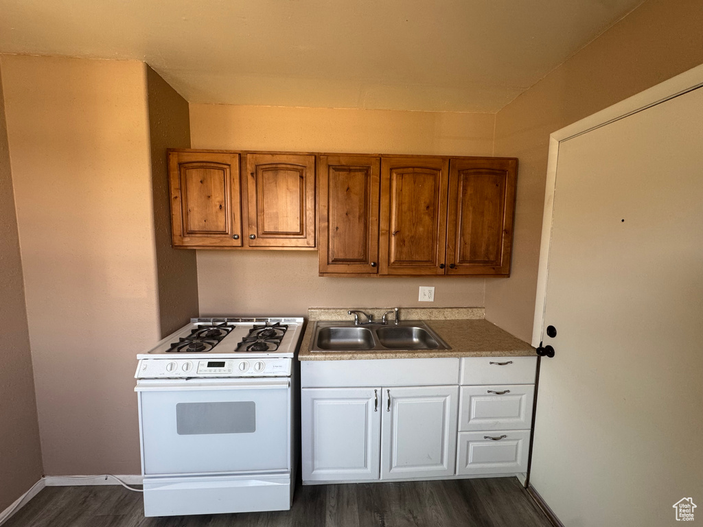 Kitchen featuring white gas range oven, dark wood-style flooring, and brown cabinetry