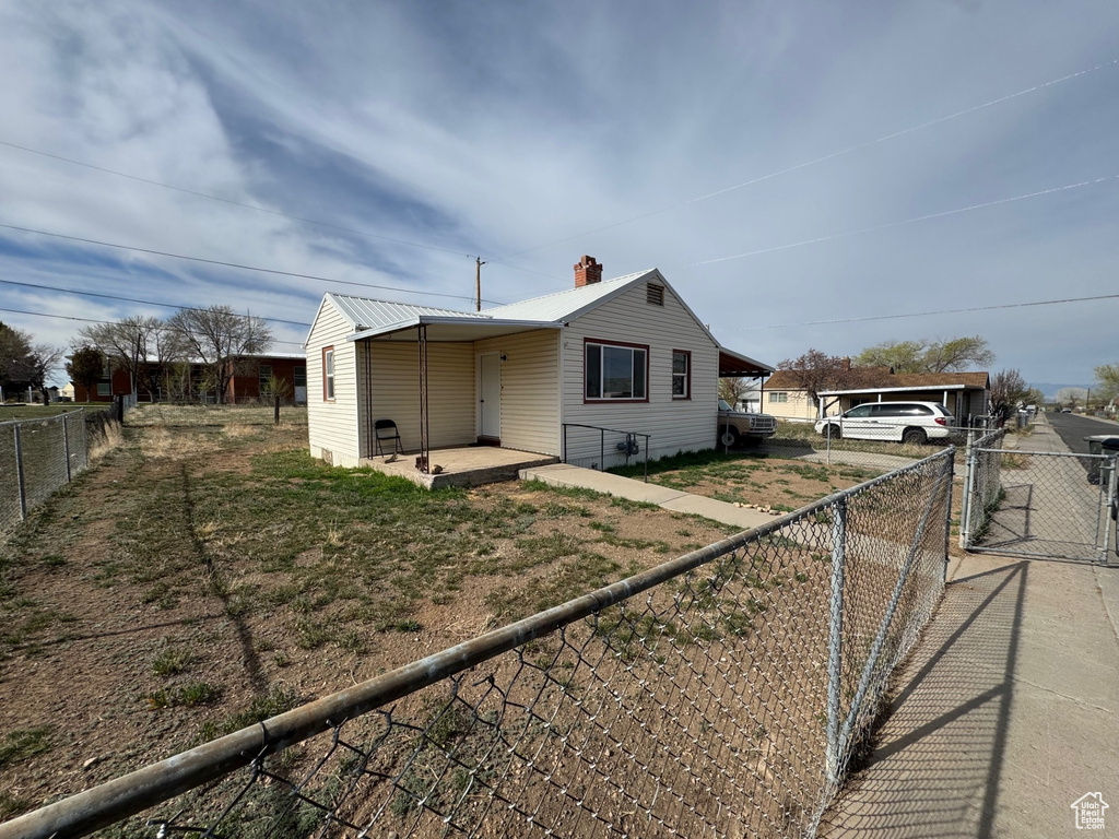 View of front facade featuring a fenced backyard, a chimney, and metal roof