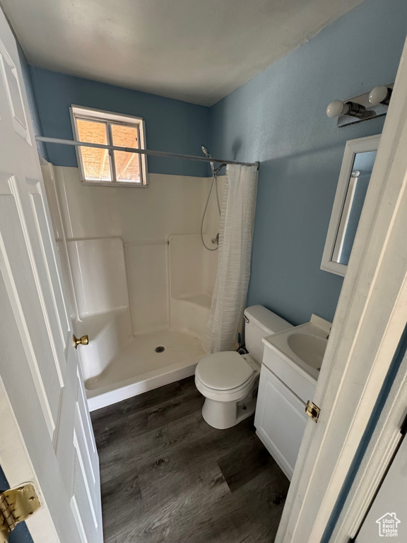 Full bath featuring curtained shower, wood finished floors, toilet, and vanity