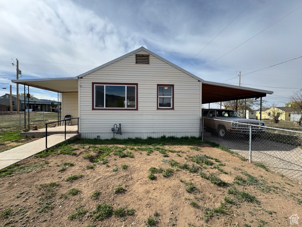 View of property exterior featuring a carport, driveway, and fence