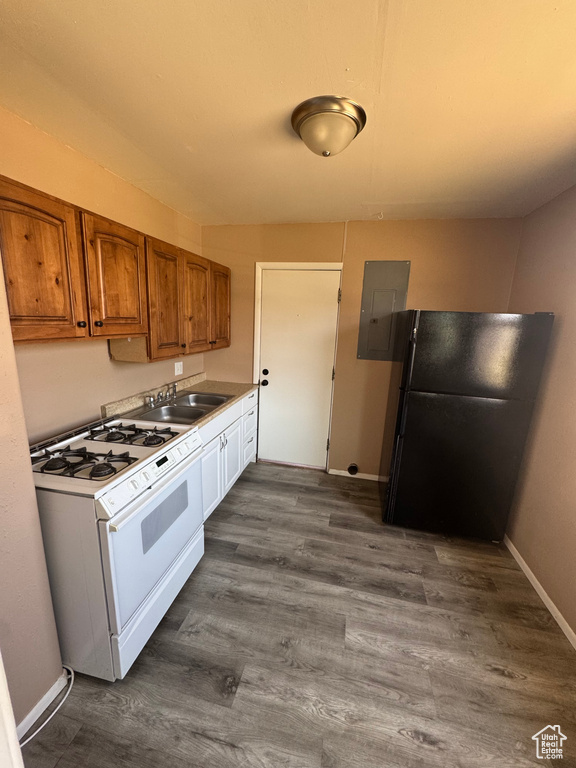 Kitchen with white gas range oven, freestanding refrigerator, electric panel, brown cabinetry, and dark wood finished floors