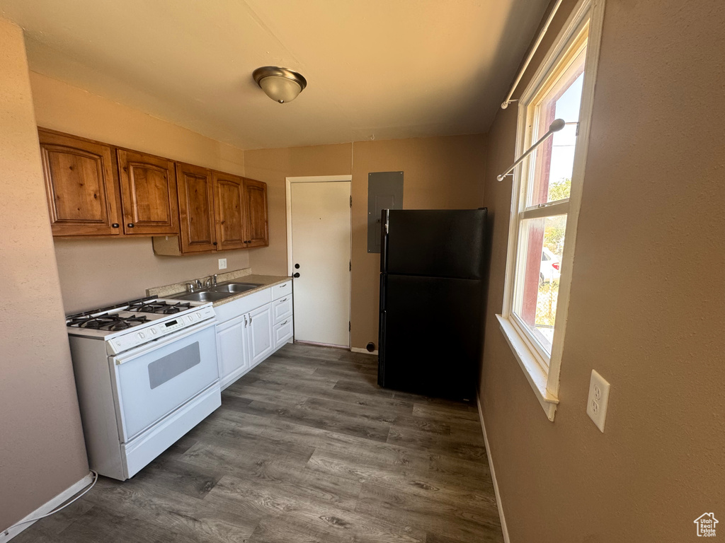 Kitchen featuring white gas range, freestanding refrigerator, brown cabinetry, dark wood finished floors, and electric panel