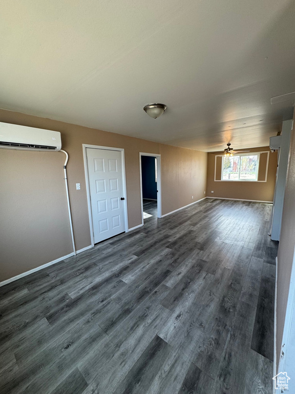 Spare room featuring baseboards, dark wood finished floors, and a wall mounted air conditioner