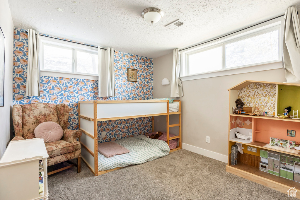 Bedroom with wallpapered walls, a textured ceiling, carpet, and baseboards