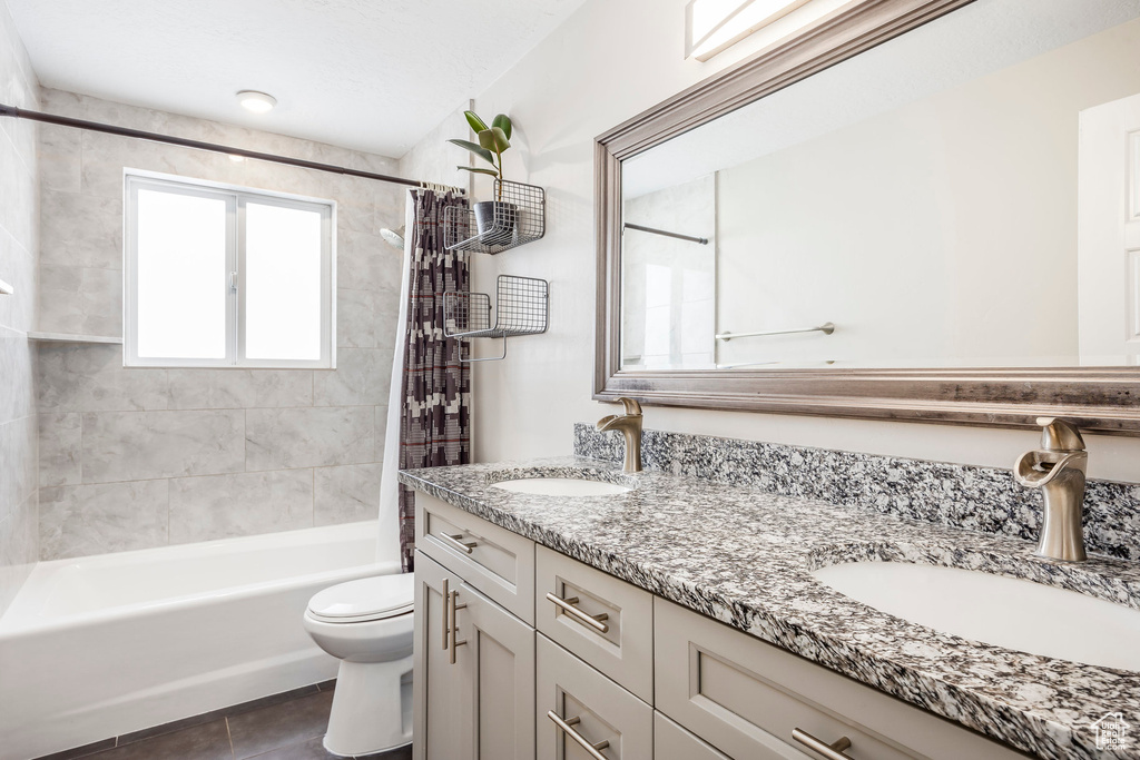 Bathroom with double vanity, toilet, tile patterned floors, and shower / bath combination with curtain