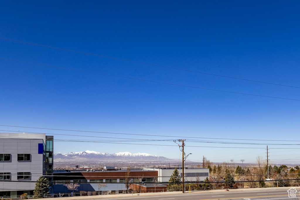 View of asphalt street featuring street lights, a mountain view, curbs, and sidewalks
