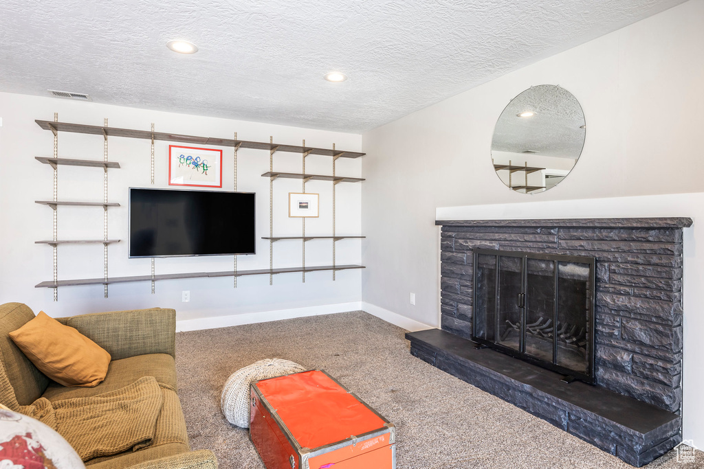 Carpeted living area featuring a textured ceiling, a fireplace, baseboards, and recessed lighting