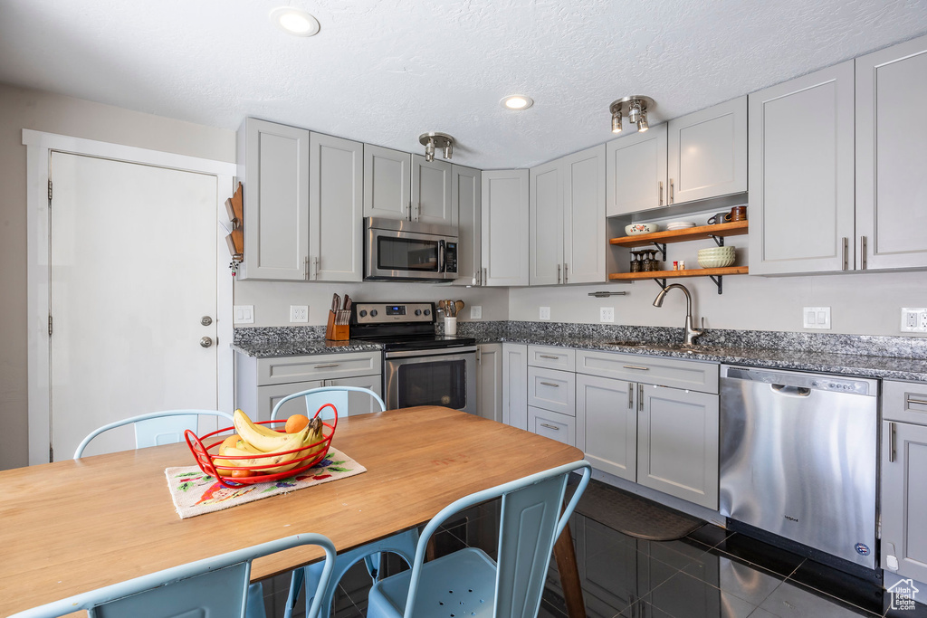 Kitchen featuring stainless steel appliances, a sink, open shelves, recessed lighting, and a textured ceiling
