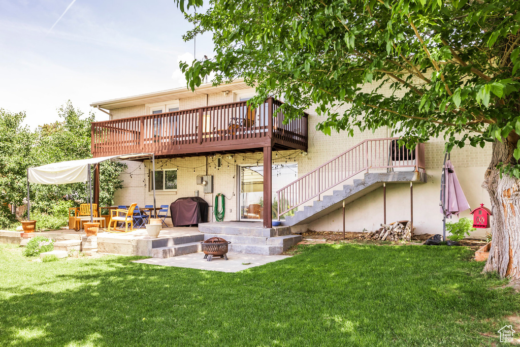 Back of house featuring an outdoor fire pit, brick siding, a patio, a yard, and stairs