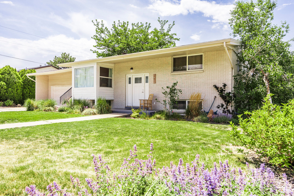 View of front of house with a front lawn, an attached garage, and brick siding