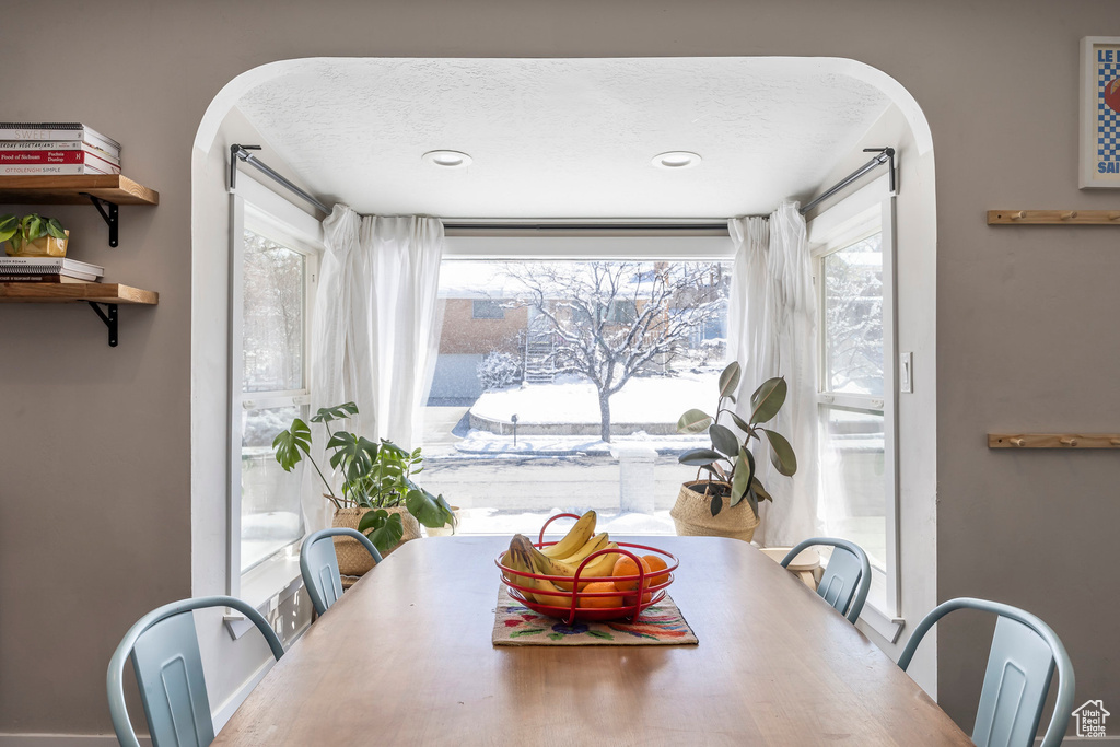 Dining room featuring arched walkways, healthy amount of natural light, and a textured ceiling