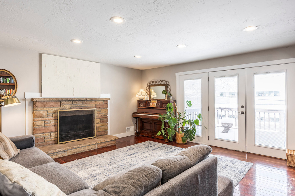 Living room featuring a fireplace, wood finished floors, french doors, recessed lighting, and a textured ceiling