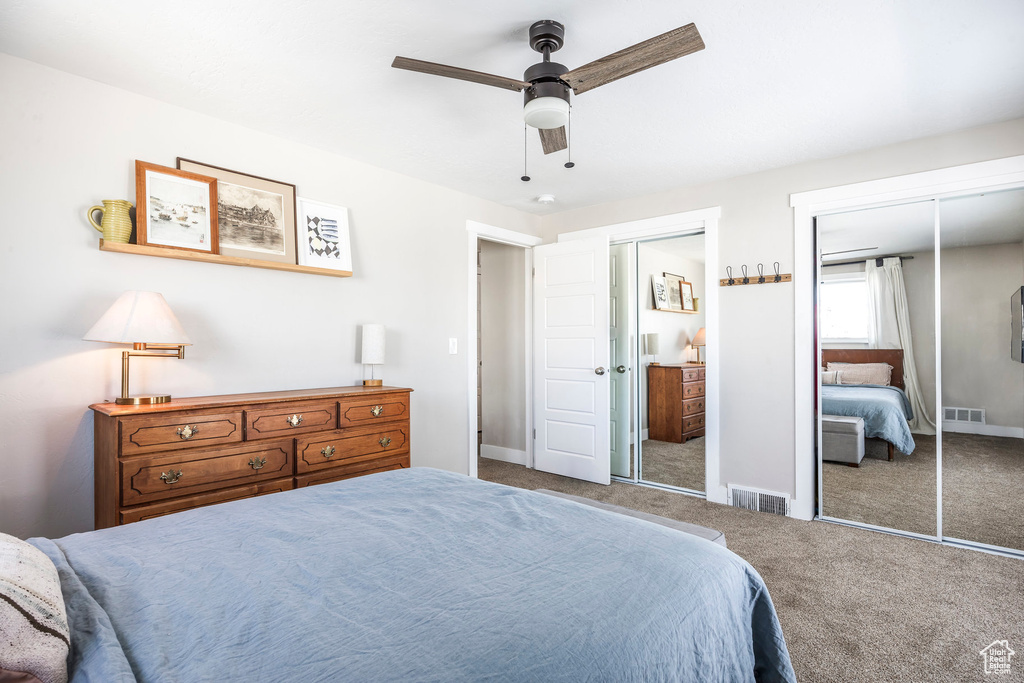 Carpeted bedroom with multiple closets, a ceiling fan, and baseboards