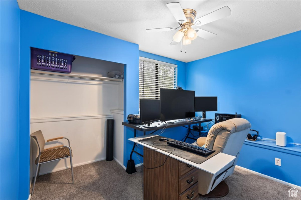 Carpeted home office featuring baseboards and ceiling fan