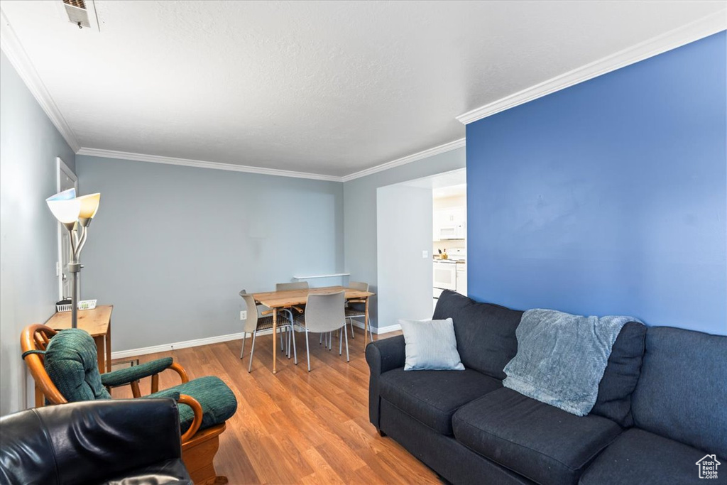 Living room with baseboards, ornamental molding, and wood finished floors