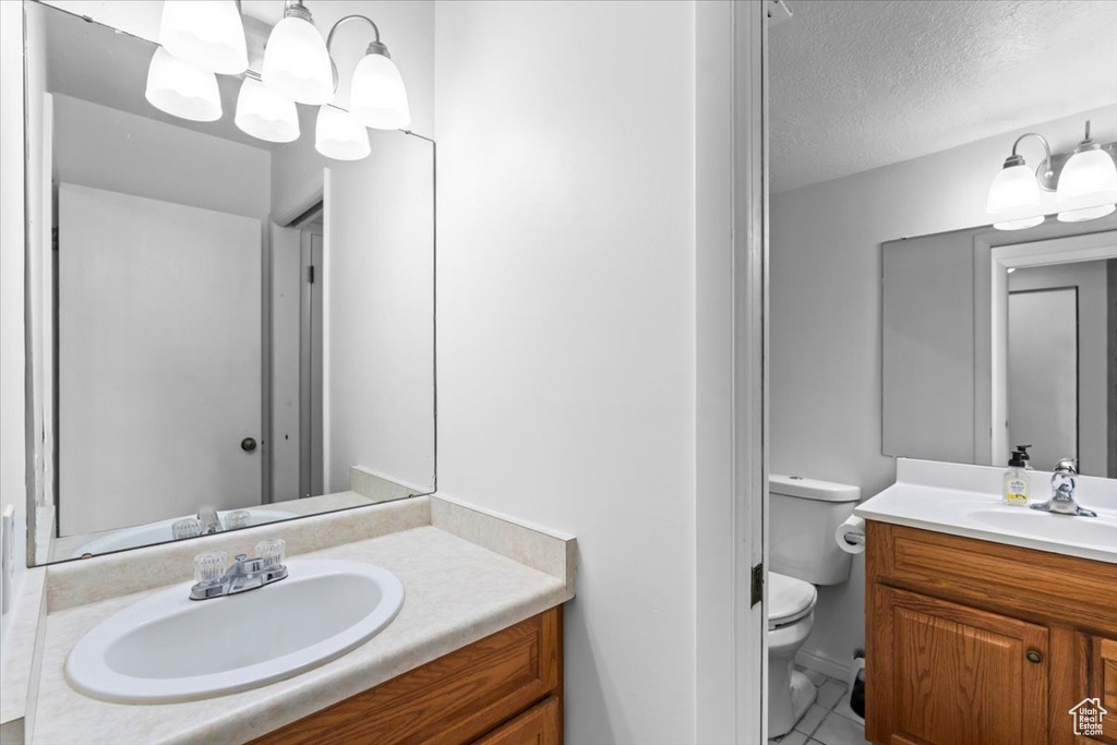 Bathroom with tile patterned flooring, a textured ceiling, toilet, and vanity
