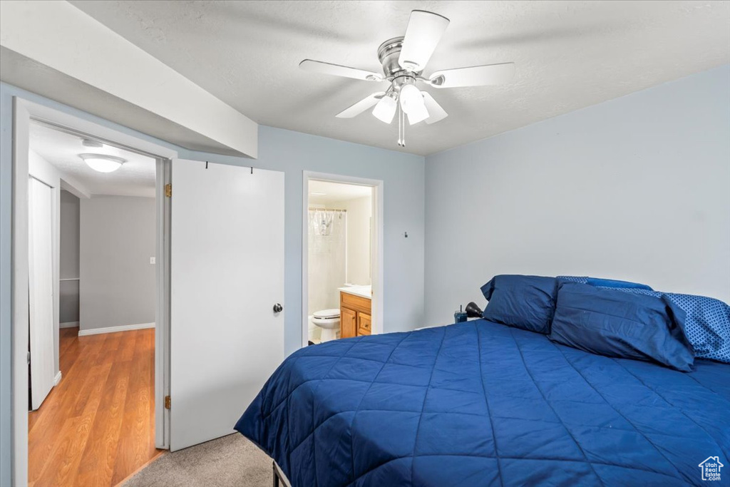 Bedroom featuring ensuite bathroom, light wood-style floors, and a ceiling fan