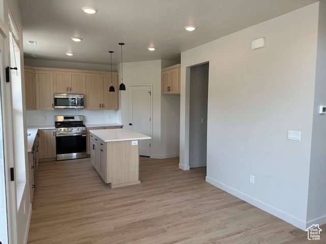 Kitchen with appliances with stainless steel finishes, light brown cabinets, decorative backsplash, light countertops, and light wood-style flooring