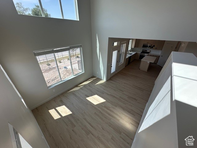 Living area featuring a towering ceiling, wood finished floors, and healthy amount of natural light