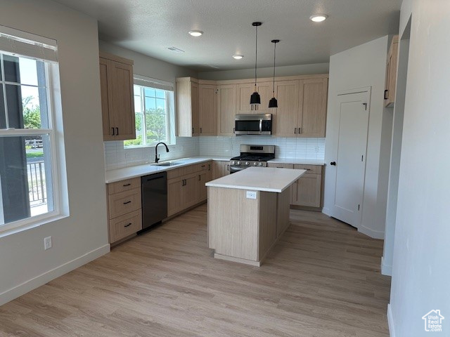Kitchen with stainless steel appliances, decorative backsplash, light countertops, light wood-style floors, and recessed lighting